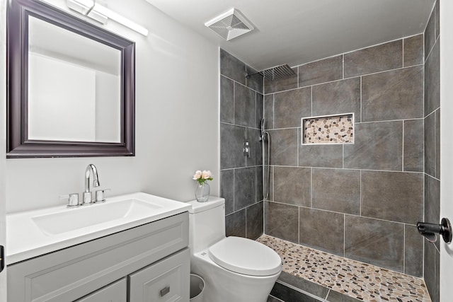 bathroom with vanity, toilet, and a tile shower