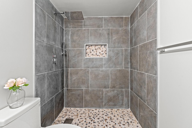 bathroom featuring a tile shower and toilet