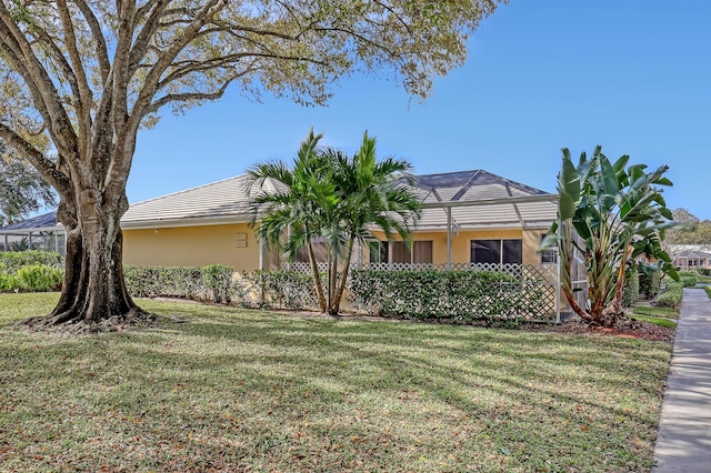 view of front of home featuring a front lawn and glass enclosure