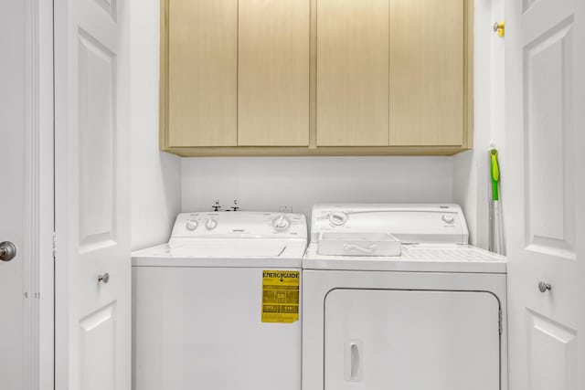 clothes washing area with separate washer and dryer and cabinets