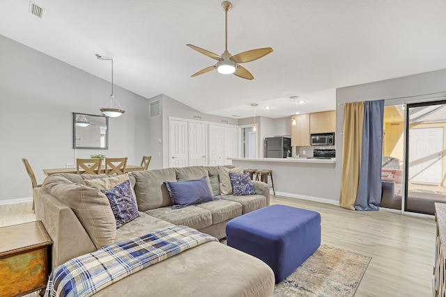 living room featuring lofted ceiling, ceiling fan, and light wood-type flooring