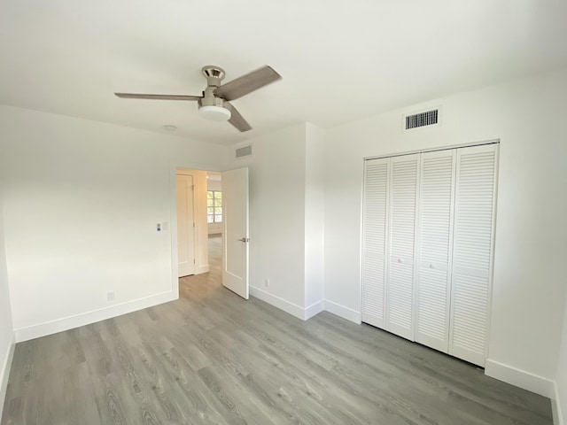 unfurnished bedroom featuring light wood-type flooring, ceiling fan, and a closet