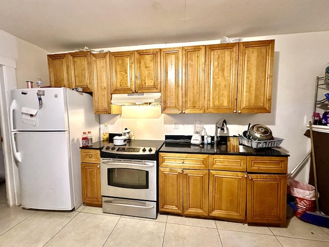 kitchen with white refrigerator, light tile patterned floors, and stainless steel electric range