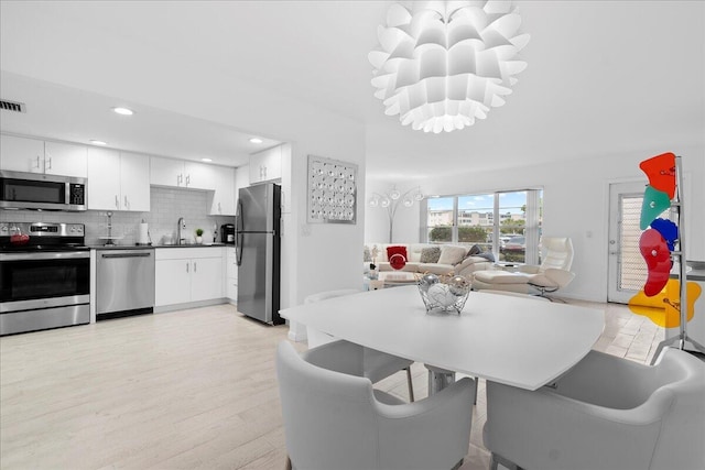 dining room featuring recessed lighting, visible vents, light wood-style floors, and a notable chandelier