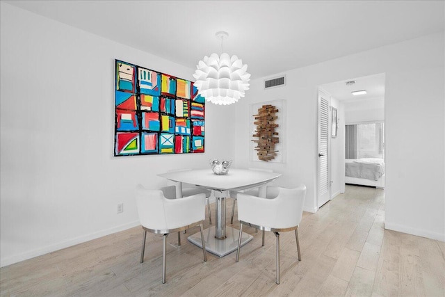 dining area with baseboards, wood finished floors, visible vents, and a notable chandelier
