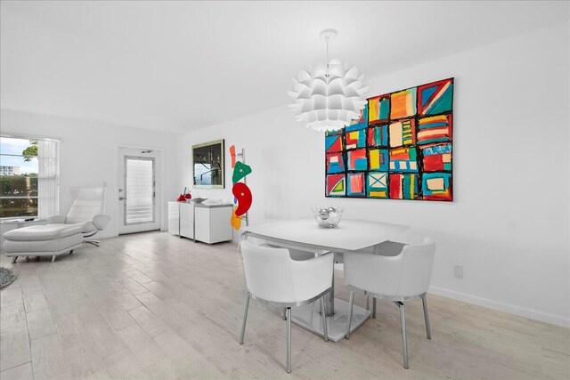 dining space with wood finished floors, baseboards, and a notable chandelier