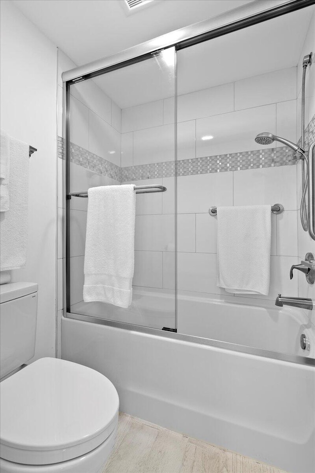 bathroom with combined bath / shower with glass door and toilet