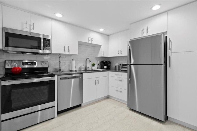 kitchen with dark countertops, white cabinets, appliances with stainless steel finishes, and a sink