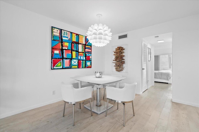 dining area with visible vents, baseboards, an inviting chandelier, and wood finished floors