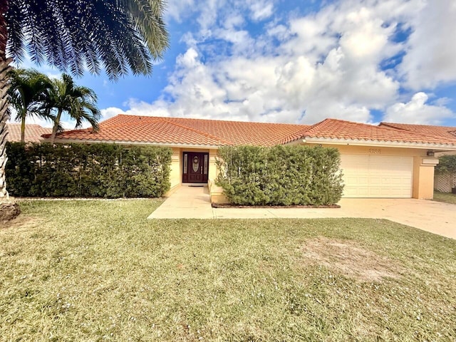 mediterranean / spanish house featuring a garage and a front lawn