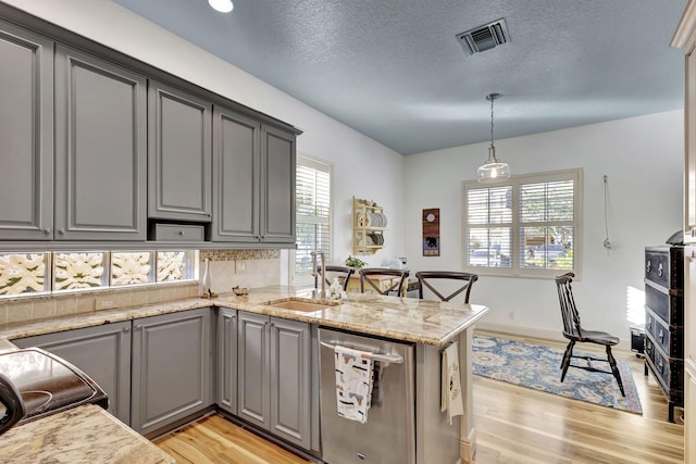 kitchen with gray cabinets, pendant lighting, sink, stainless steel dishwasher, and kitchen peninsula