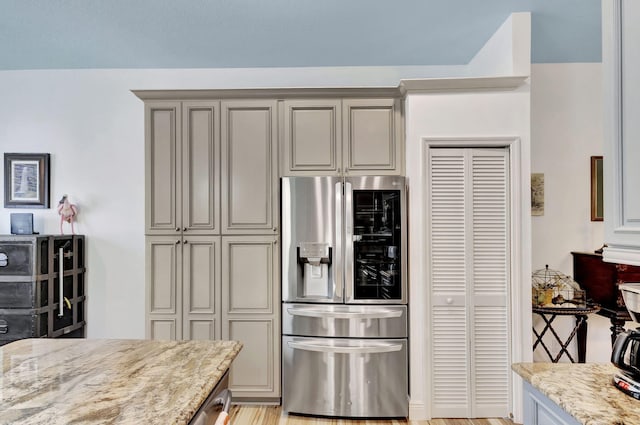 kitchen featuring gray cabinetry, stainless steel fridge with ice dispenser, and light stone countertops