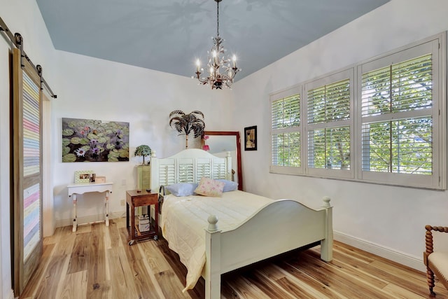 bedroom with a notable chandelier, hardwood / wood-style flooring, and a barn door