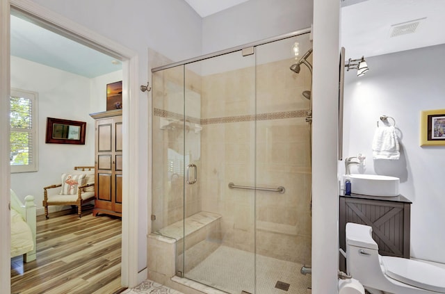 bathroom with hardwood / wood-style flooring, walk in shower, sink, and toilet