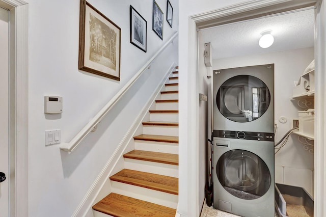 laundry room featuring a textured ceiling and stacked washing maching and dryer