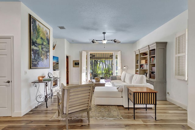 living area featuring ceiling fan, a textured ceiling, and light wood-type flooring