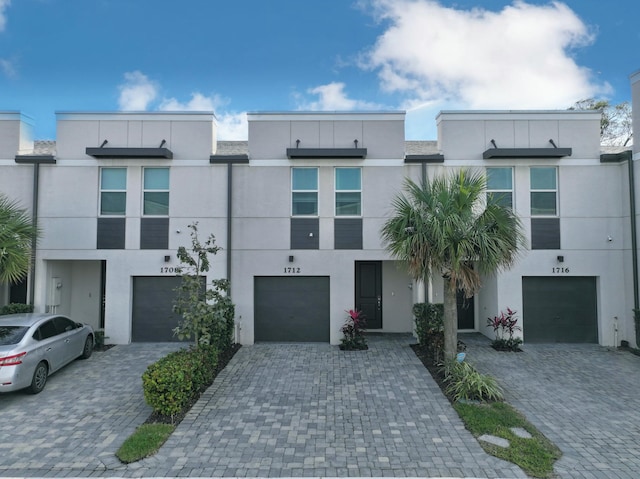 view of front of home with an attached garage, driveway, and stucco siding