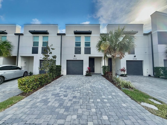 multi unit property with decorative driveway, an attached garage, and stucco siding