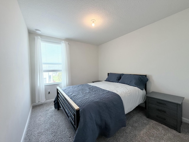 bedroom with a textured ceiling and dark colored carpet