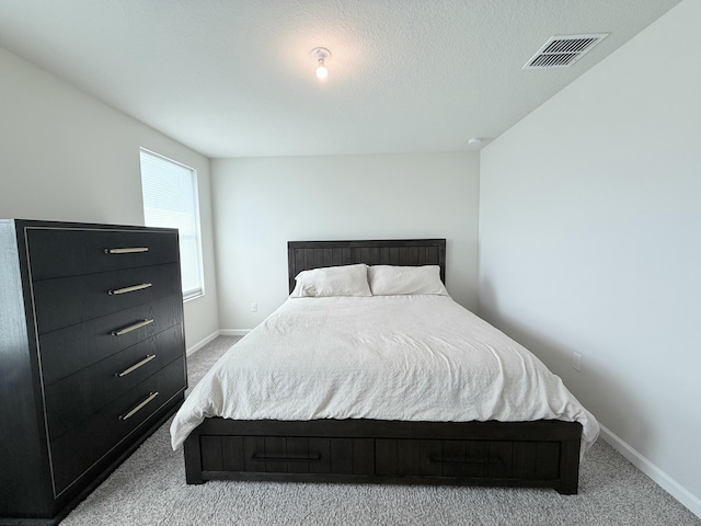 bedroom with light colored carpet and a textured ceiling