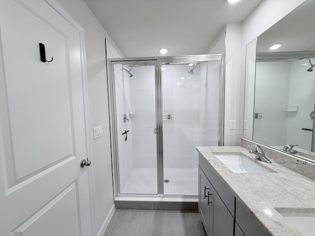 bathroom featuring wood-type flooring, a shower with door, and vanity