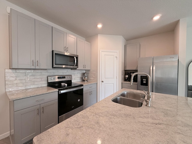 kitchen featuring gray cabinets, appliances with stainless steel finishes, sink, and light stone counters