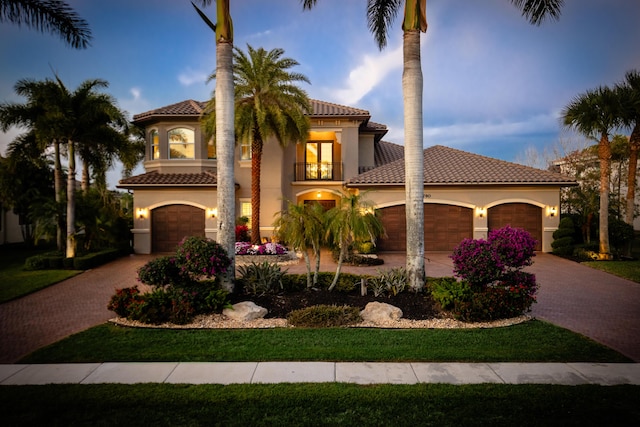 mediterranean / spanish-style home featuring stucco siding, a tiled roof, decorative driveway, and a balcony