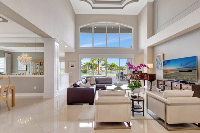 living room with an inviting chandelier, ornamental molding, decorative columns, and light tile patterned flooring