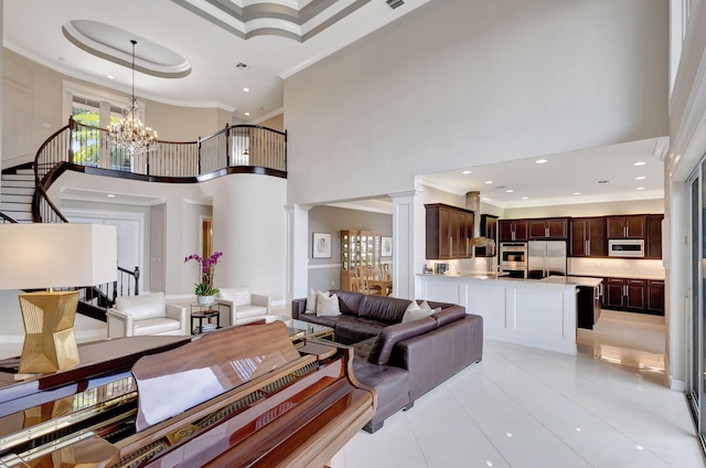 living room featuring decorative columns, crown molding, a towering ceiling, and a chandelier