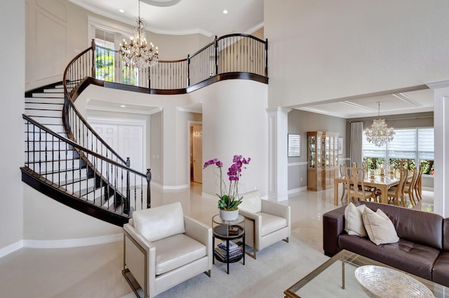 living room with ornate columns, crown molding, a towering ceiling, and a chandelier