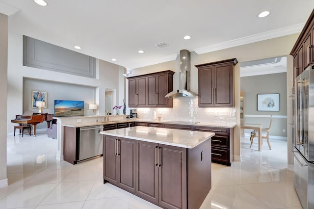 kitchen with wall chimney exhaust hood, a center island, appliances with stainless steel finishes, kitchen peninsula, and decorative backsplash