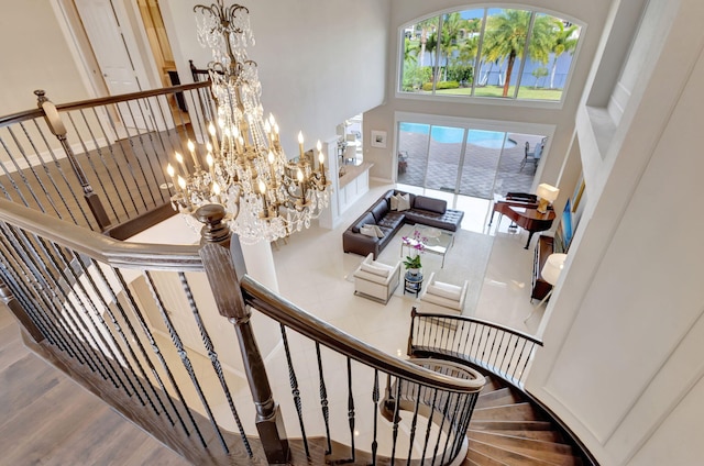 stairway featuring wood-type flooring, a towering ceiling, and an inviting chandelier