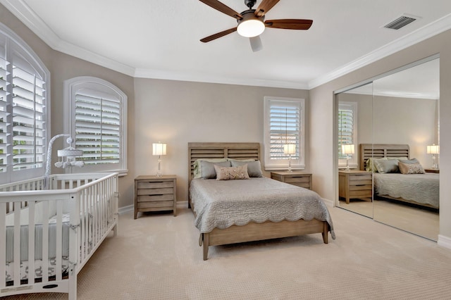 carpeted bedroom featuring crown molding, ceiling fan, and a closet