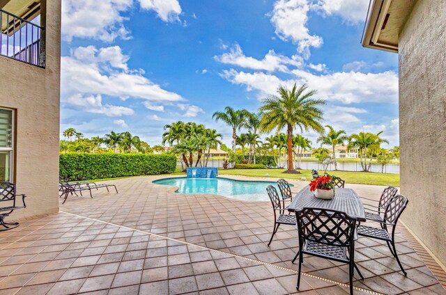 view of pool featuring a water view, pool water feature, a patio area, and a lawn