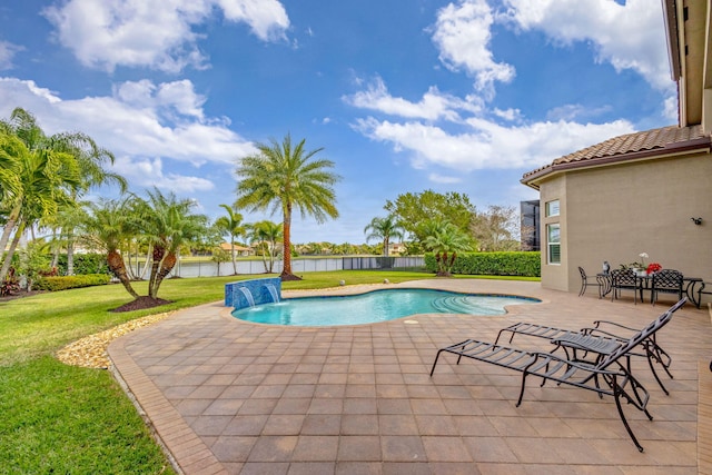 view of swimming pool featuring a lawn, pool water feature, a water view, and a patio area