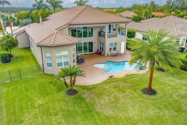 rear view of house with a balcony, a fenced in pool, a patio area, and a lawn