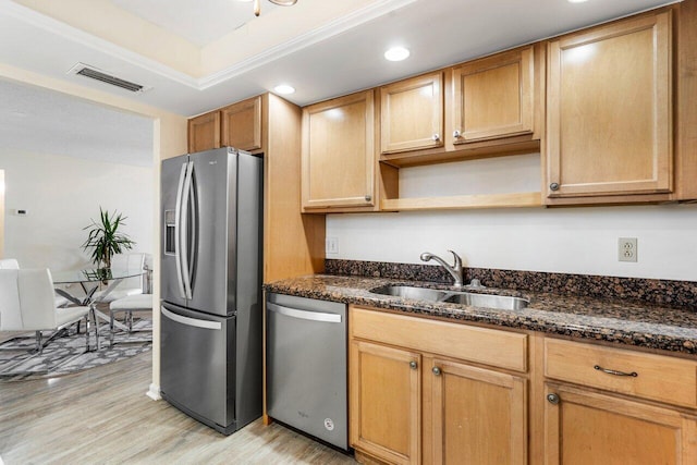 kitchen with sink, dark stone countertops, light hardwood / wood-style floors, stainless steel appliances, and crown molding