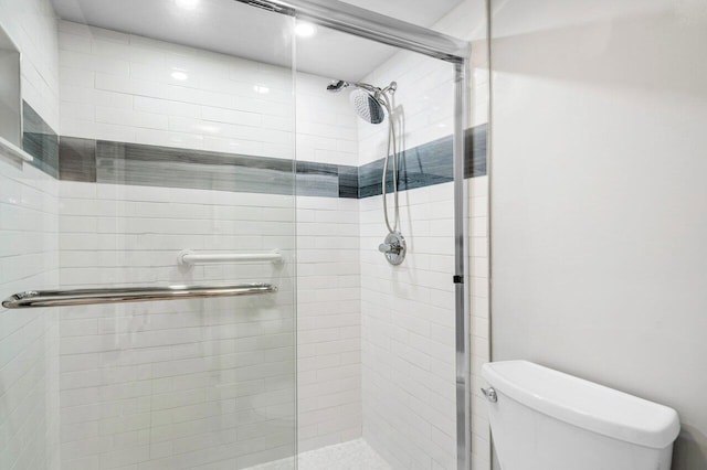 bathroom with a shower with shower door and toilet