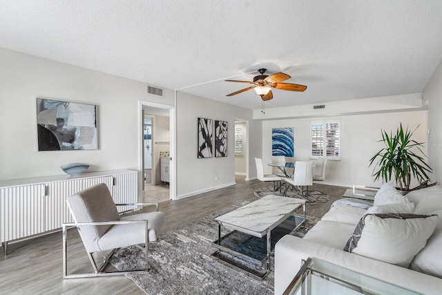 living room with ceiling fan, hardwood / wood-style flooring, and a textured ceiling