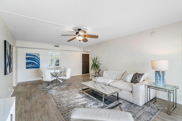 living room featuring ceiling fan, wood-type flooring, and a textured ceiling