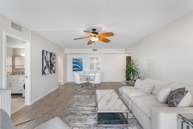 living room with hardwood / wood-style floors, a textured ceiling, and ceiling fan