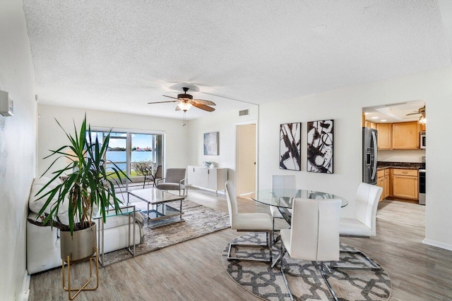 dining room featuring ceiling fan, a textured ceiling, and light wood-type flooring