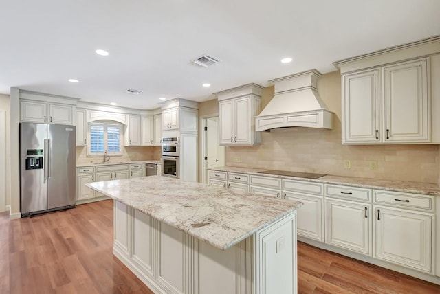 kitchen with sink, decorative backsplash, a center island, stainless steel appliances, and custom range hood