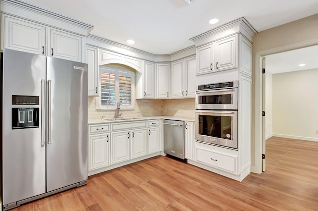 kitchen featuring light wood-type flooring, stainless steel appliances, sink, and white cabinets