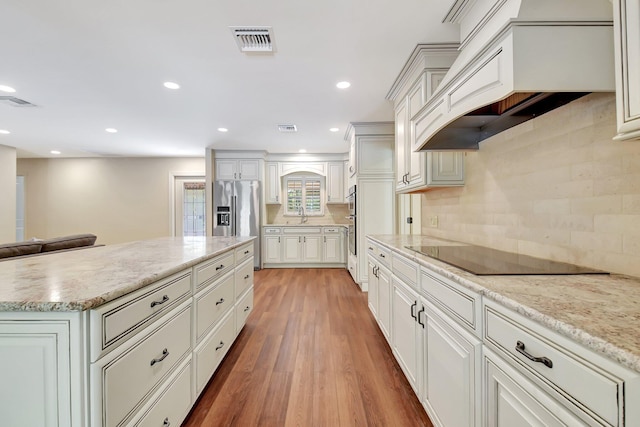 kitchen featuring high end fridge, custom exhaust hood, dark hardwood / wood-style floors, black electric stovetop, and backsplash