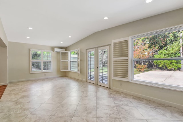 spare room featuring french doors, lofted ceiling, a wall unit AC, and a wealth of natural light