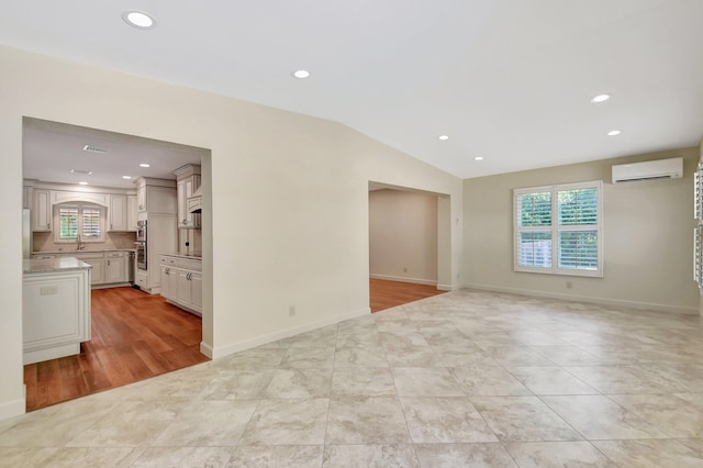 tiled spare room featuring vaulted ceiling, sink, and a wall mounted air conditioner