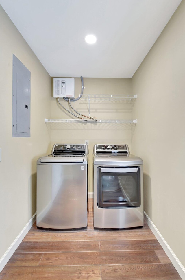 washroom featuring hardwood / wood-style flooring, washing machine and clothes dryer, and electric panel