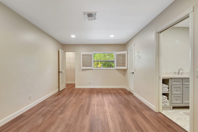 unfurnished bedroom with sink and light hardwood / wood-style floors