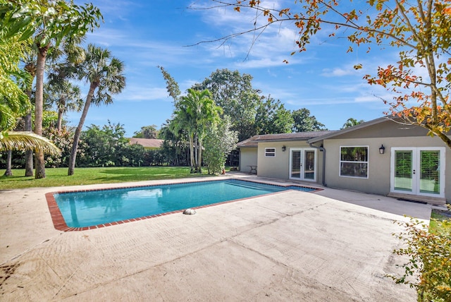 view of swimming pool featuring french doors, a patio, and a lawn